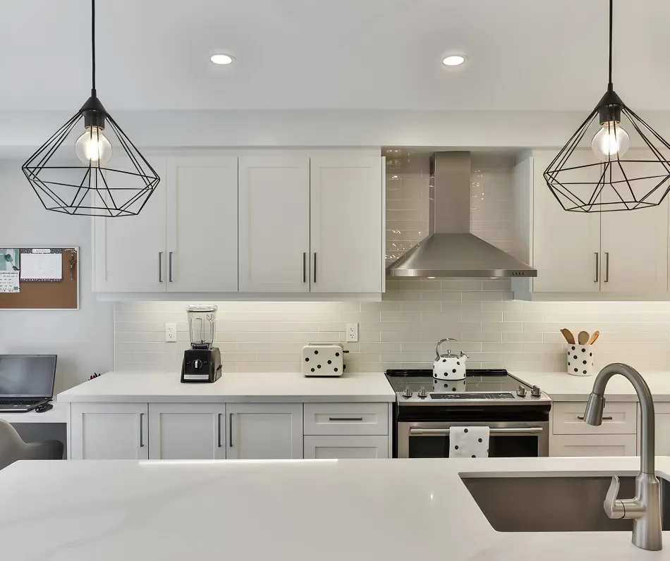A clean, empty kitchen with white cabinets and wiped worktops